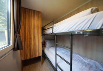 Habitación con literas, armario de madera y ventana en Cottage en Kaatsheuvel, Países Bajos.