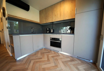 Moderne Küchenzeile in der Domus Lodge in Kaatsheuvel, Niederlande, mit Holzverkleidung und Geräten.