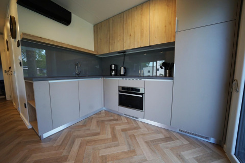 Modern kitchen interior at Domus lodge in Kaatsheuvel, Netherlands, with wood accents and built-in appliances.