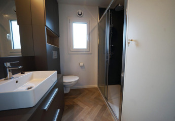 Baño moderno en la cabaña Domus, Kaatsheuvel, Países Bajos, con ducha, inodoro y lavabo minimalista.