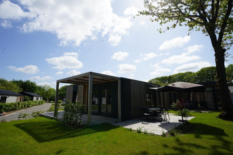 Photo of Domus lodge in Kaatsheuvel, Netherlands, modern architecture, patio, green lawn, and sunny weather.