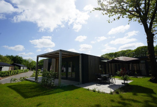 Photo of Domus lodge in Kaatsheuvel, Netherlands, modern architecture, patio, green lawn, and sunny weather.