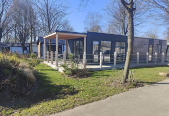 Moderne Domus-lodge te Kaatsheuvel in Nederland, met houten terras, grote ramen en groene omgeving.