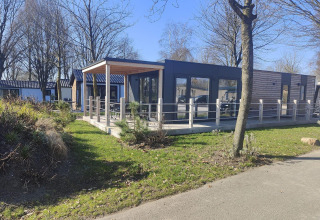 Modern Domus lodge at Kaatsheuvel in the Netherlands, featuring a wooden terrace, large windows and greenery.