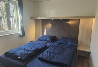Kamer met twee eenpersoonsbedden, blauwe lakens en raam, in de Domus-lodge in Kaatsheuvel, Nederland.