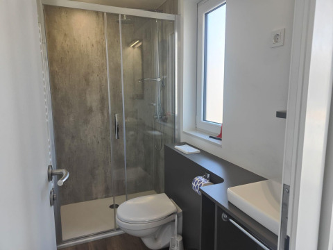 Modern bathroom at Domus lodge in Kaatsheuvel, Netherlands with shower, toilet, window and sink.