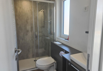 Moderne badkamer in Domus lodge te Kaatsheuvel, Nederland, met douche, toilet, raam en lavabo.