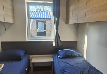 Kamer in Domus-lodge in Kaatsheuvel, Nederland, met twee bedden, opbergruimte en uitzicht naar buiten.