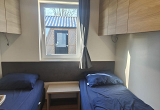 Room at Domus lodge in Kaatsheuvel, Netherlands, with twin beds, storage cabinets, and outside view.
