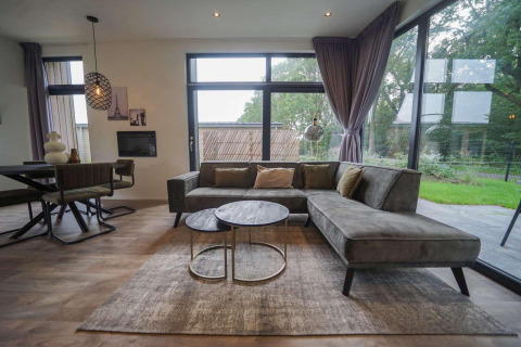Moderne woonkamer in Pavilion Maximaal lodge te Kaatsheuvel, Nederland, met grote ramen en uitzicht.