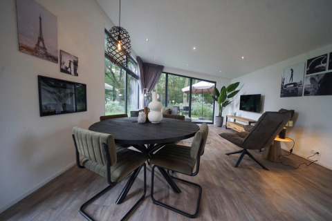 Modernes Wohnzimmer und Essbereich in der Pavilion Maximaal Lodge in Kaatsheuvel, Niederlande, mit großen Fenstern.