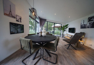 Zona de estar y comedor moderna en la lodge Pavilion Maximaal en Kaatsheuvel, Países Bajos, con grandes ventanales.