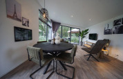 Modern living and dining area at Pavilion Maximaal lodge in Kaatsheuvel, Netherlands, with large windows.