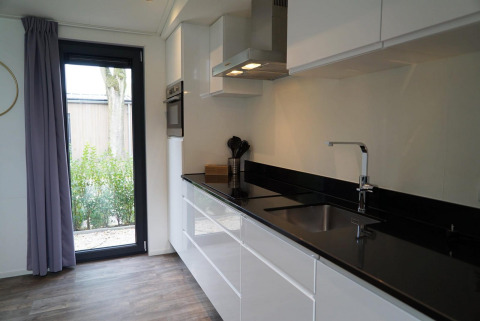 Modern kitchen inside Pavilion Maximaal lodge at Kaatsheuvel, Netherlands, featuring sleek black countertops.