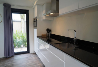 Cocina moderna en el lodge Pavilion Maximaal en Kaatsheuvel, Países Bajos, con encimeras negras elegantes.