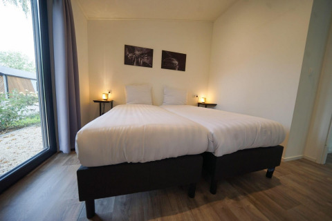 Lichte slaapkamer met twee eenpersoonsbedden, grote ramen en minimalistische inrichting in Pavilion Maximaal, Kaatsheuvel.