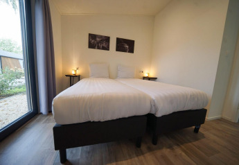 Helles Schlafzimmer mit zwei Einzelbetten, großen Fenstern und moderner Einrichtung im Pavilion Maximaal, Kaatsheuvel.