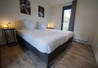 Schlafzimmer im Pavilion Maximaal Lodge in Kaatsheuvel, Niederlande, mit zwei Betten und modernen Möbeln.