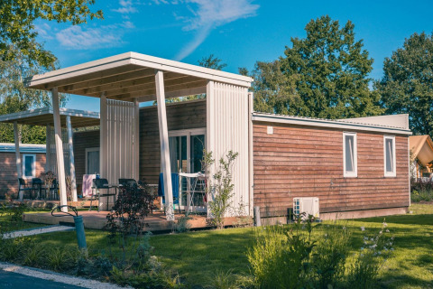 Lodge Tiny Cottage moderno en Kaatsheuvel, Países Bajos, rodeado de jardín verde y árboles.