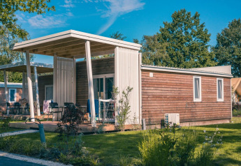 Moderne Tiny Cottage Lodge in Kaatsheuvel, Niederlande, umgeben von grünem Rasen und Bäumen.