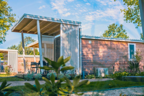 Modern Tiny Cottage lodge in Kaatsheuvel, Netherlands, featuring wood siding and a shaded outdoor terrace.