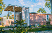 Moderne Tiny Cottage Lodge in Kaatsheuvel, Niederlande, mit Holzverkleidung und überdachter Terrasse.