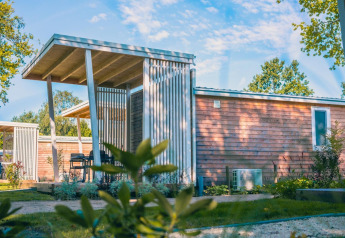 Moderne Tiny Cottage lodge i Kaatsheuvel, Holland, med træfacade og overdækket terrasse under blå himmel.