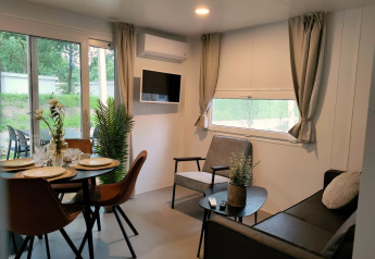 Moderne woon- en eetruimte in Tiny Cottage te Kaatsheuvel, Nederland, met stijlvol interieur en grote ramen.