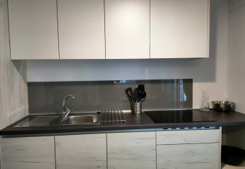 Moderne keuken in Tiny Cottage te Kaatsheuvel, Nederland, met witte kasten en een donkere werkblad.