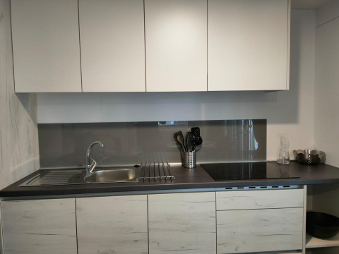 Cucina moderna al Tiny Cottage di Kaatsheuvel, Paesi Bassi, con mobili bianchi e piano nero elegante.