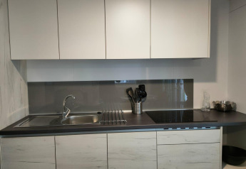 Cucina moderna al Tiny Cottage di Kaatsheuvel, Paesi Bassi, con mobili bianchi e piano nero elegante.