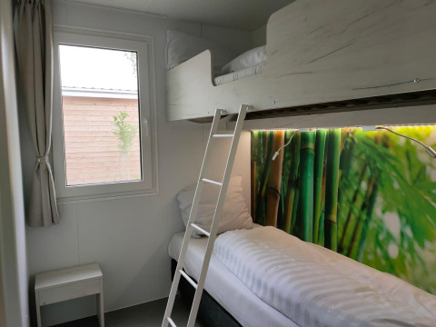 Et lille værelse i Tiny Cottage ved Kaatsheuvel, Holland, med køjesenge og farverigt bambus-motiv.