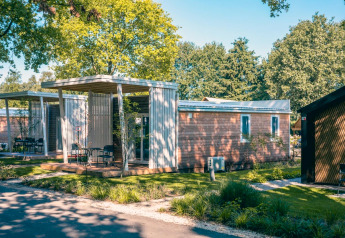 Moderne Tiny Cottage-lodges in Kaatsheuvel, Nederland, omgeven door groene bomen en nette tuinen.