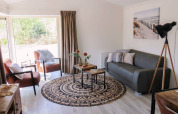 Bright lounge area in a lodge with modern furnishings, large windows, grey sofa, and stylish décor.