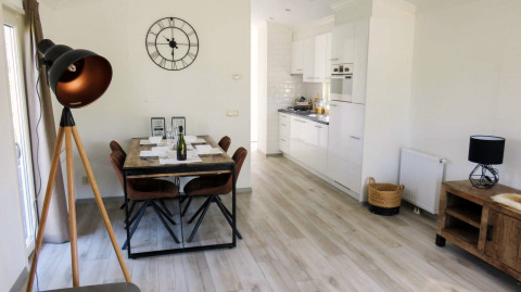 Bright lodge interior featuring a dining area, modern kitchen, floor lamp, and decorative wall clock.