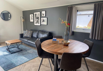 Moderne leefruimte in Velthorst lodge in Kaatsheuvel, Nederland, met zetel, wanddecoratie en eettafel.
