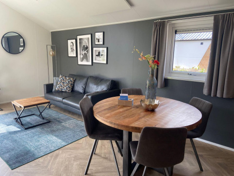 Sala moderna en la cabaña Velthorst en Kaatsheuvel, Países Bajos, con sofá, arte mural y comedor.