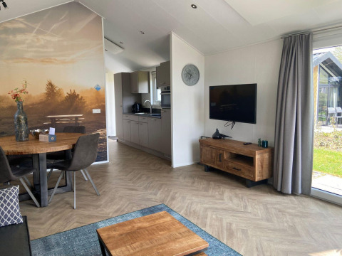 Sala moderna en un lodge Velthorst en Kaatsheuvel, Países Bajos, con suelos de madera y gran mural.