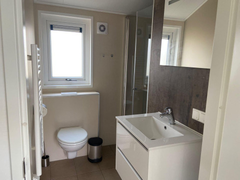 Un baño moderno en una cabaña Velthorst en Kaatsheuvel, Países Bajos, con inodoro, lavabo y ducha.