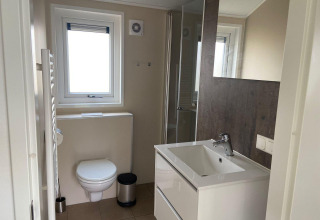 Un baño moderno en una cabaña Velthorst en Kaatsheuvel, Países Bajos, con inodoro, lavabo y ducha.