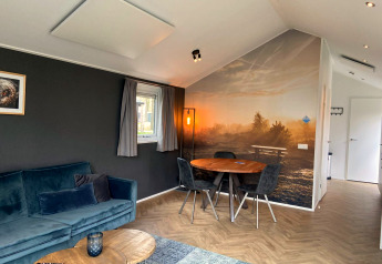 Soggiorno moderno nella lodge Velthorst a Kaatsheuvel, Paesi Bassi, con murale naturale e tavolo da pranzo.