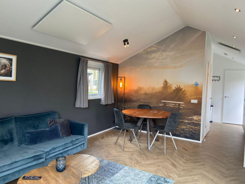 Soggiorno moderno nella lodge Velthorst a Kaatsheuvel, Paesi Bassi, con murale naturale e tavolo da pranzo.