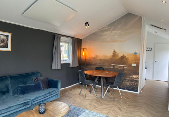 Moderne leefruimte in Velthorst-lodge, Kaatsheuvel, Nederland, met natuurmuur en eettafel.