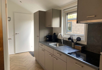 Cucina moderna della lodge Velthorst a Kaatsheuvel, Paesi Bassi, con armadi grigi e finestra.