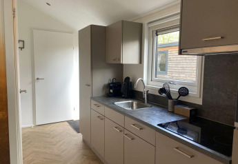 Moderne keuken in Velthorst lodge te Kaatsheuvel, Nederland, met grijze kasten en een raam.