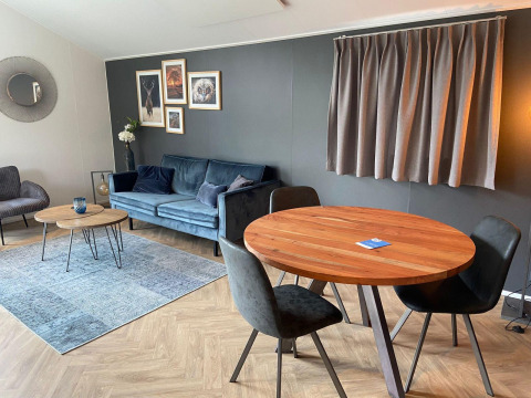 Soggiorno di lodge moderno a Velthorst, Kaatsheuvel, con divano, tavolo da pranzo, arte murale e decorazioni.