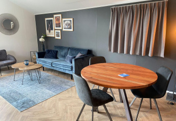 Moderne lodge woonkamer in Velthorst, Kaatsheuvel, met zetel, eettafel, wanddecoratie en gezellige stijl.