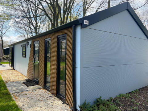 Moderno lodge Velthorst en Kaatsheuvel, Países Bajos, con fachada de madera y árboles alrededor.