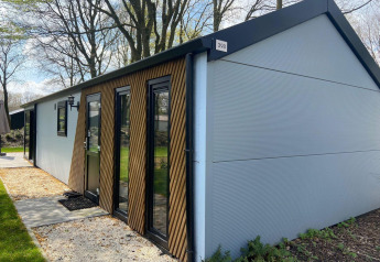 Moderne Velthorst-lodge in Kaatsheuvel, Nederland, met houten accenten en omringd door bomen en gras.