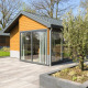 Moderne chalet Velthorst med træbeklædning, store vinduer og flisebelagt terrasse med beplantning.